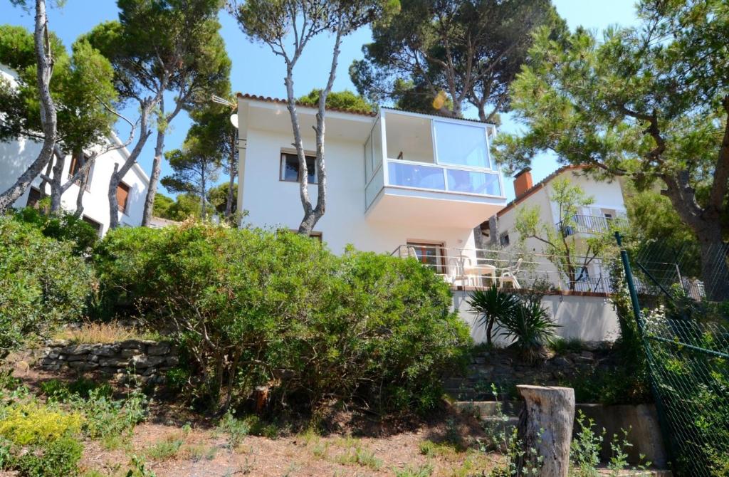 une maison blanche avec des arbres devant elle dans l'établissement Apartamento Ilse, à L'Estartit