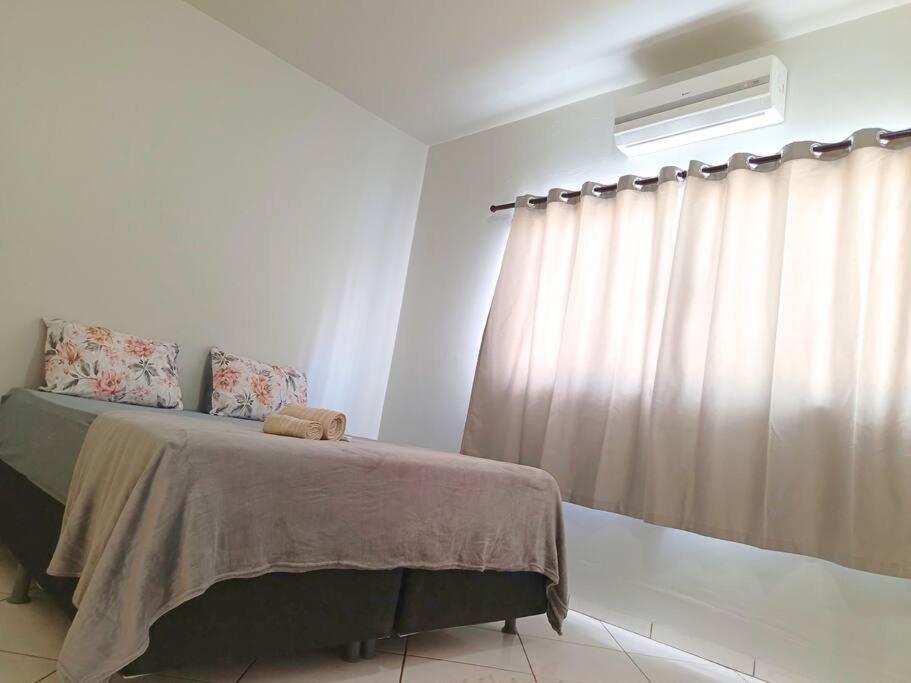 een slaapkamer met een bed en een raam met gordijnen bij Lindo Apto105 em primavera do Leste in Primavera do Leste
