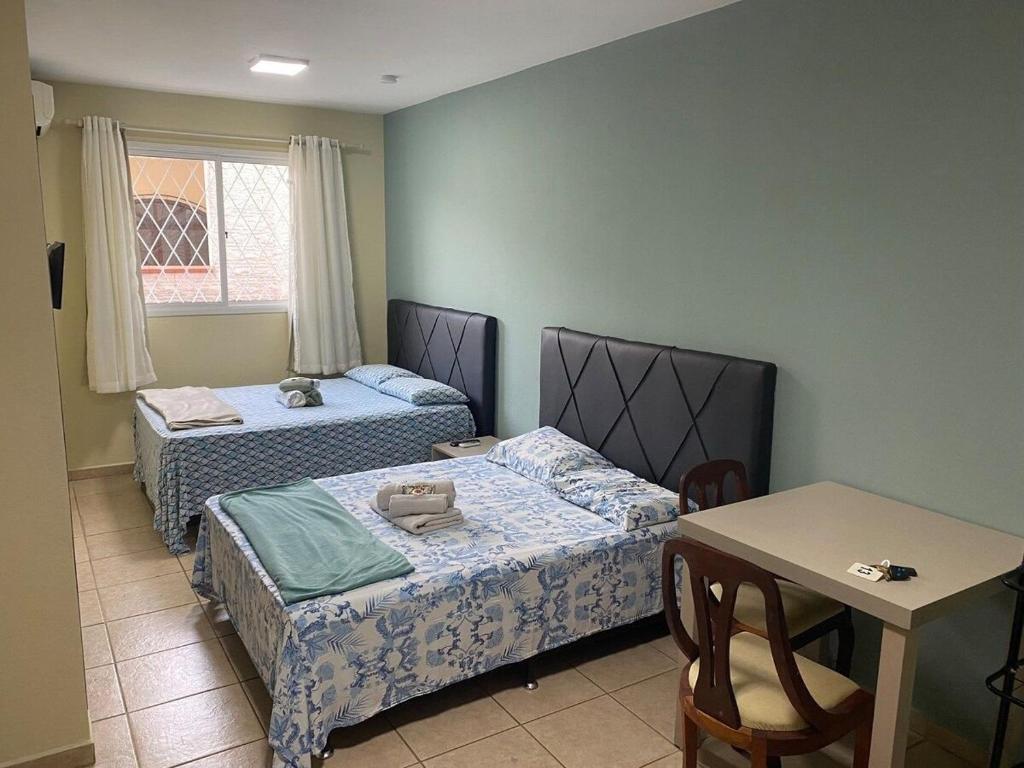 Cette chambre comprend deux lits, une table, une table et des chaises. dans l'établissement RCM Vilas - STUDIO n 03, à Joinville