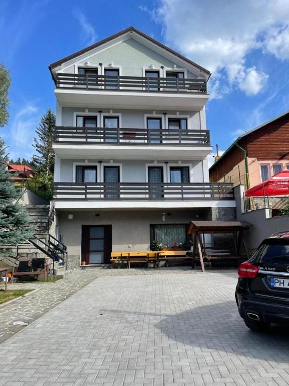 a large white building with a parking lot in front of it at Hygge House in Buşteni