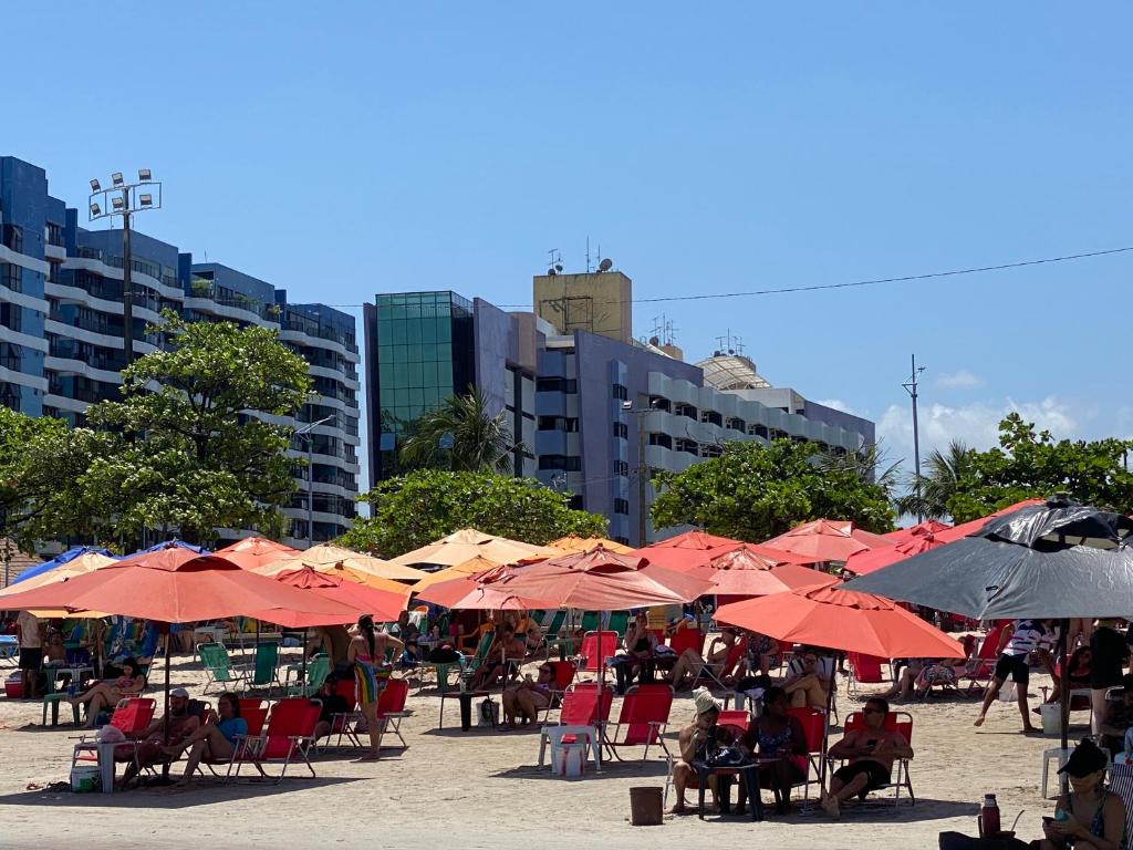 a group of tables and chairs with umbrellas on a beach at NEO I - Ap. 627 in Maceió