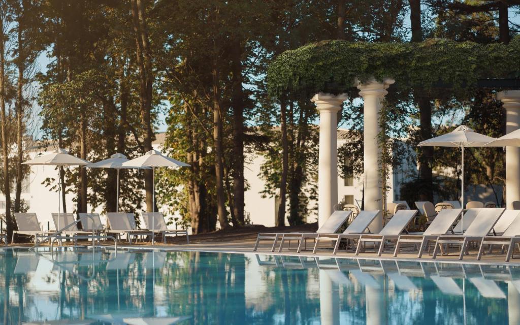 a swimming pool with white chairs and umbrellas at Astor Garden Hotel in St. St. Constantine and Helena