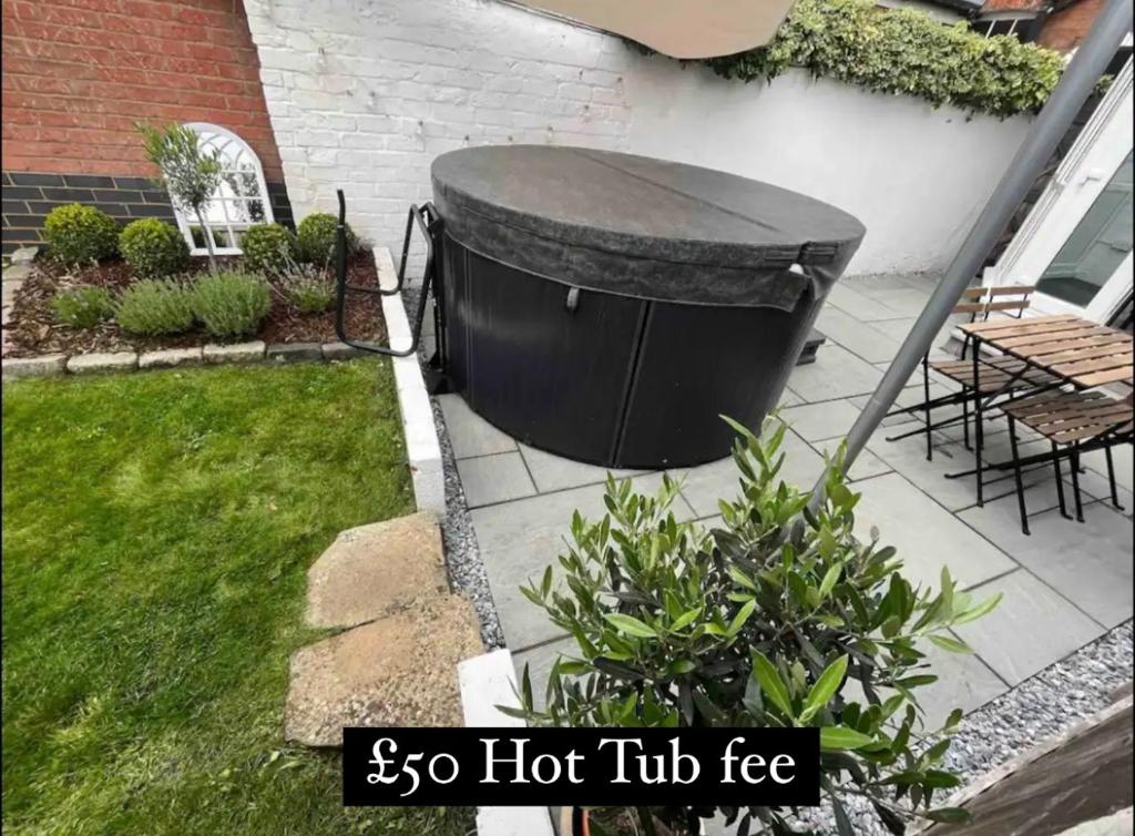 una gran bañera negra sentada junto a un patio en Central Cottage, Hot Tub, en Shottery