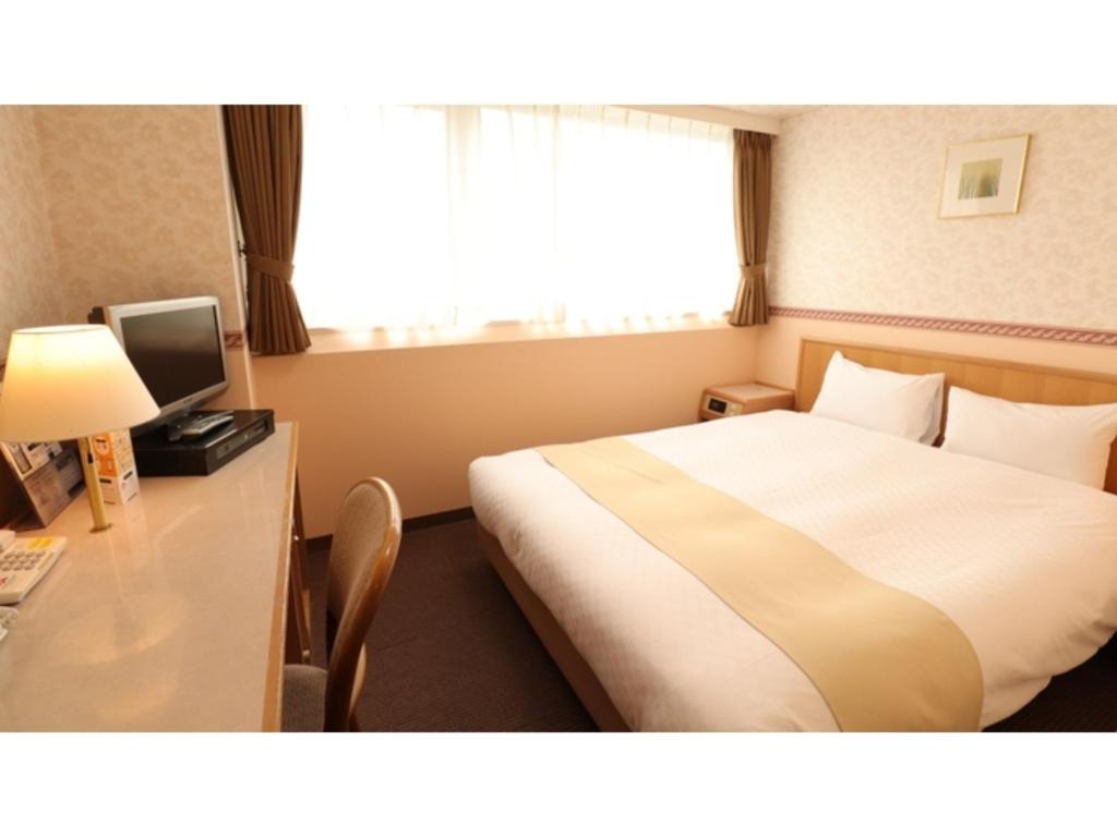 松本的住宿－Hotel Montagne Matsumoto - Vacation STAY 82920v，配有一张床、一张书桌和一扇窗户的酒店客房