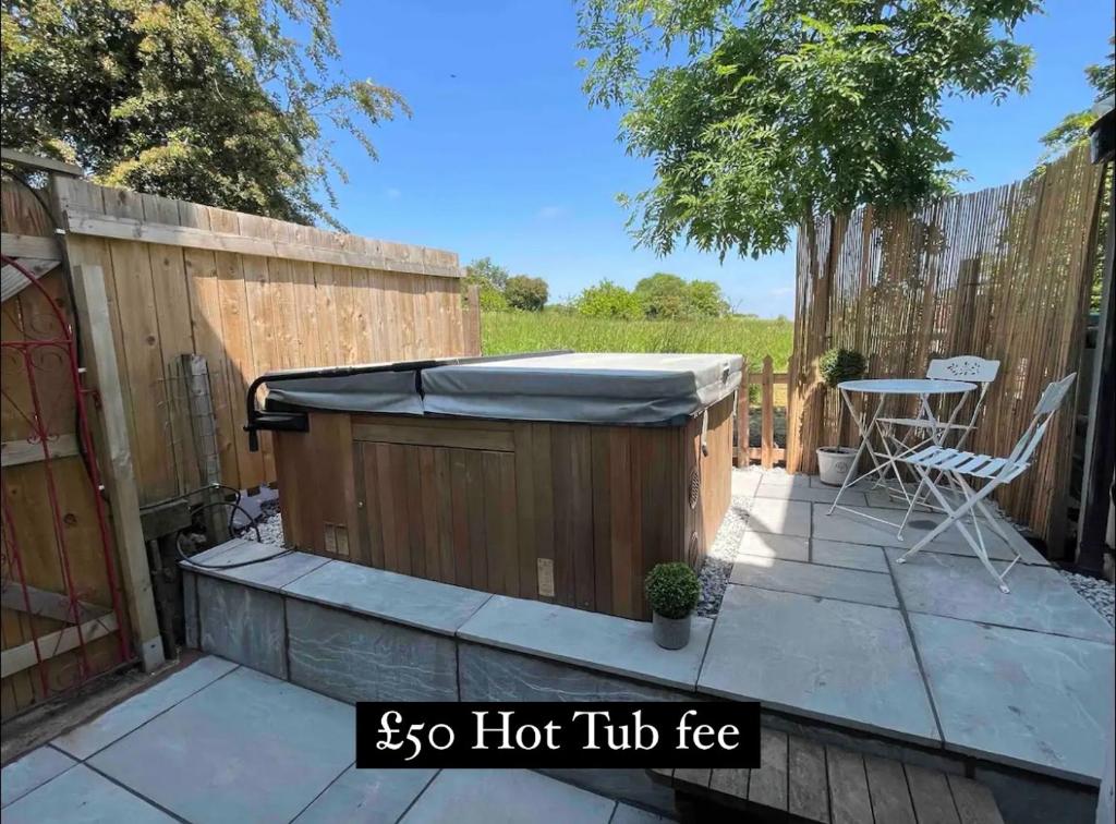 una bañera de hidromasaje en un patio trasero con una mesa en Bay Cottage, Hot Tub, en Snitterfield