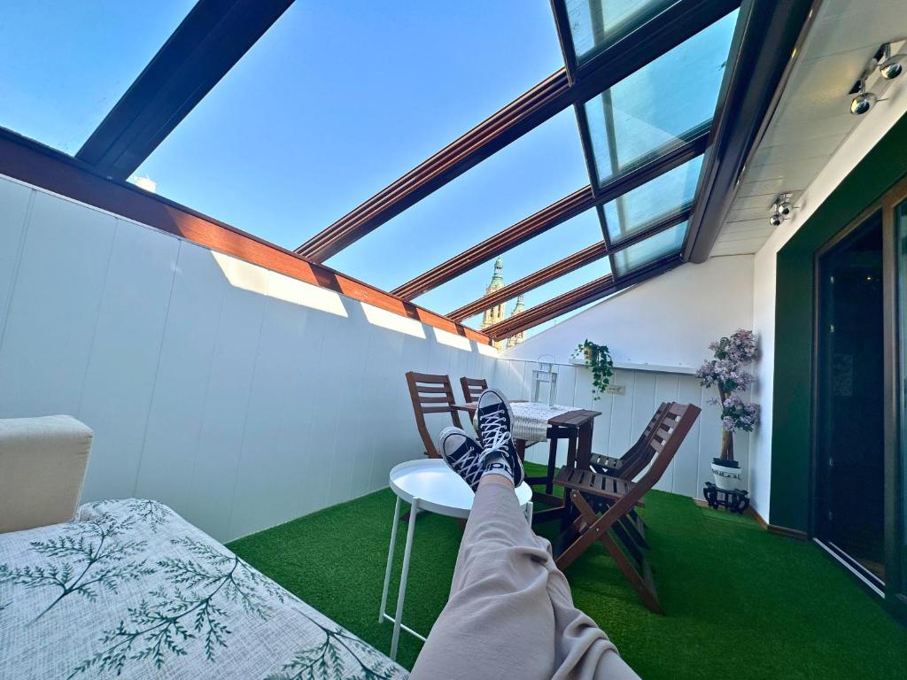 a person with their feet up on a table in a room at Dos Torres Ático - Solárium Privado en Calle Alfonso I in Zaragoza