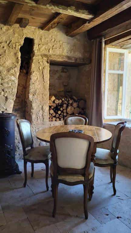 - une table et des chaises dans une pièce dotée d'une cheminée dans l'établissement Airbnb: Vieilles Pierres et Rivière en Périgord, à Couze-et-Saint-Front