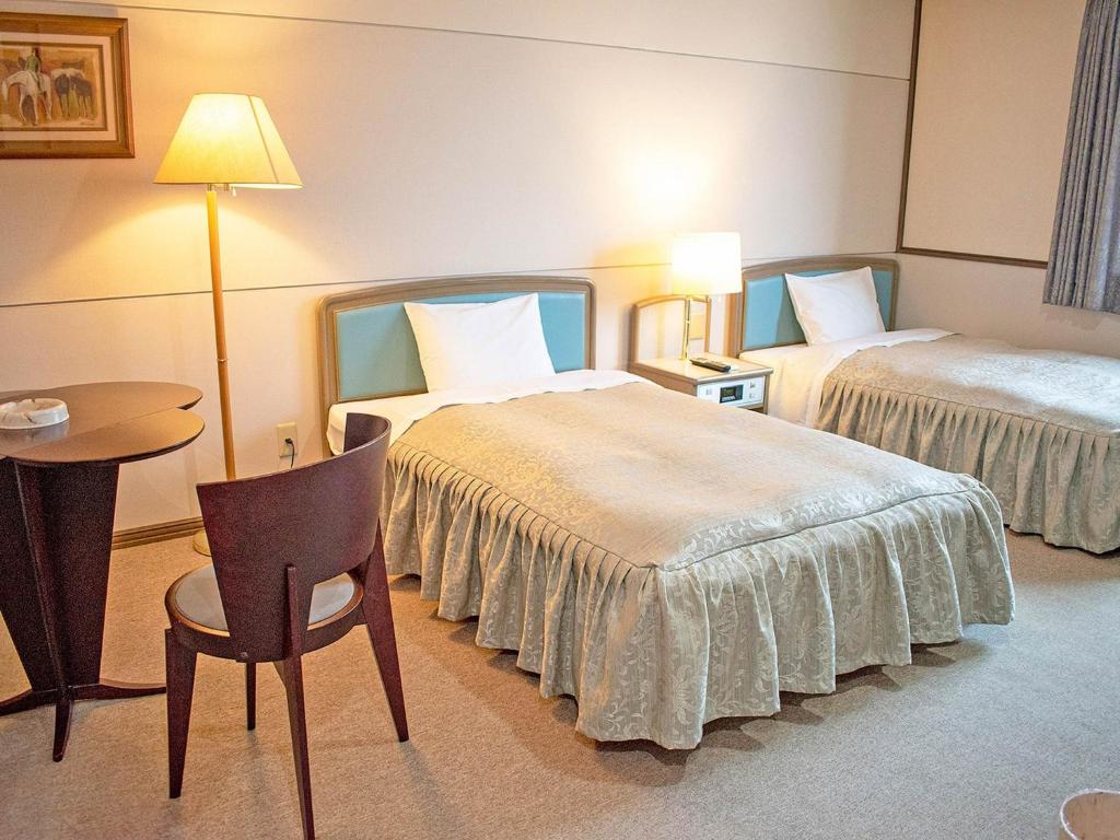 a hotel room with two beds and a table and a chair at Hotel Akaboshitei - Vacation STAY 49562v in Echizen