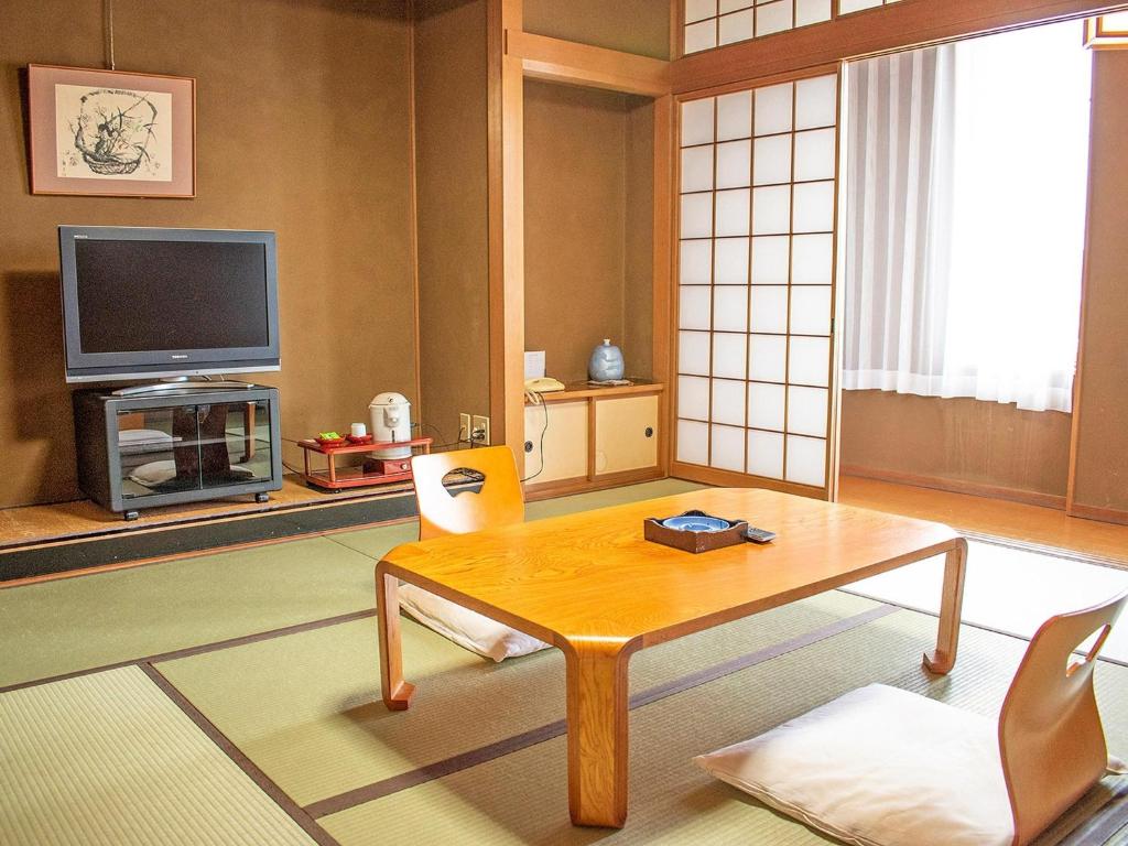 ein Wohnzimmer mit einem Tisch und einem TV in der Unterkunft Hotel Akaboshitei - Vacation STAY 49555v in Echizen