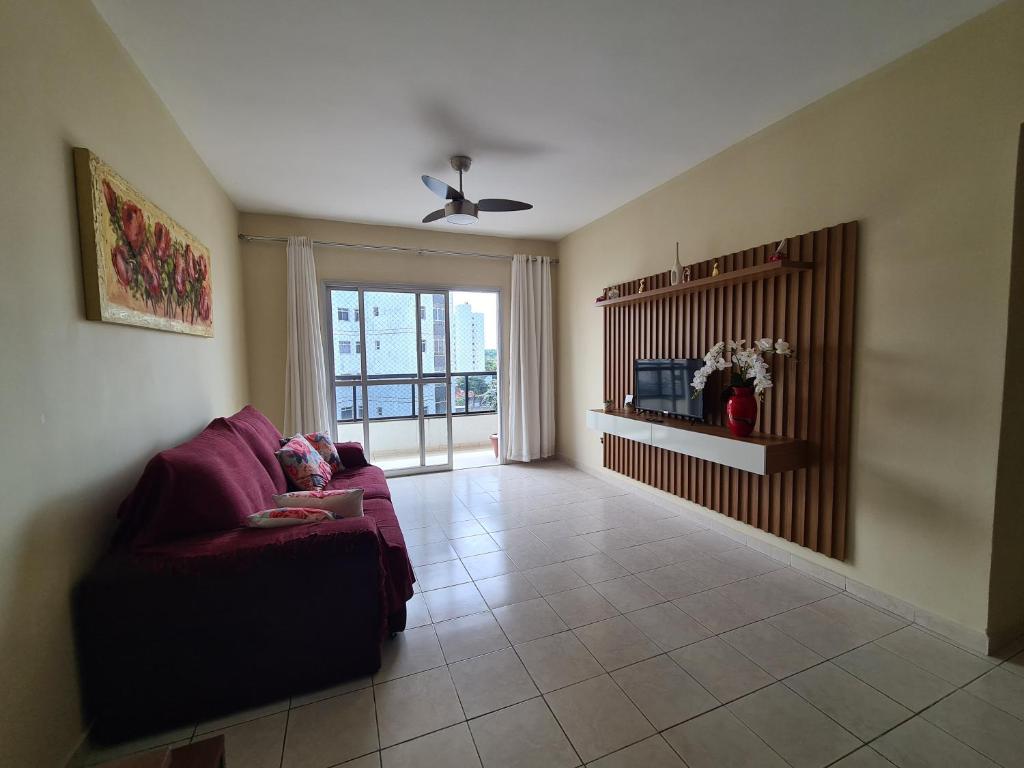 sala de estar con sofá púrpura y ventana en Praia do Morro Guarapari, en Guarapari