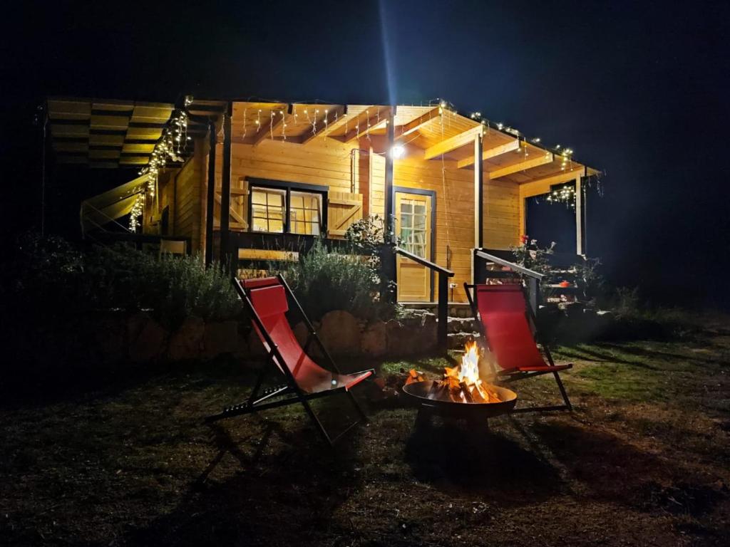 two chairs and a fire in front of a house at night at Eco Lodge nella natura "La Grande Quercia" in Calangianus