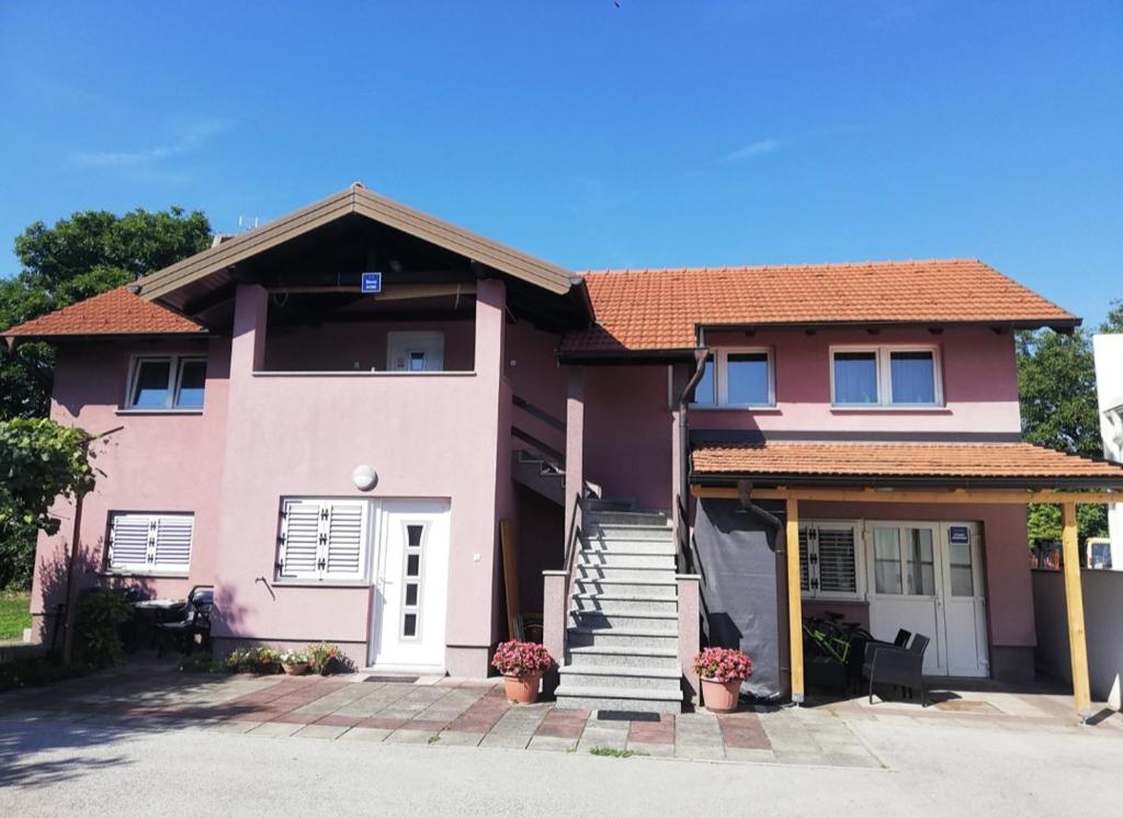 a pink house with stairs and a porch at Guest House Lucija in Zagreb