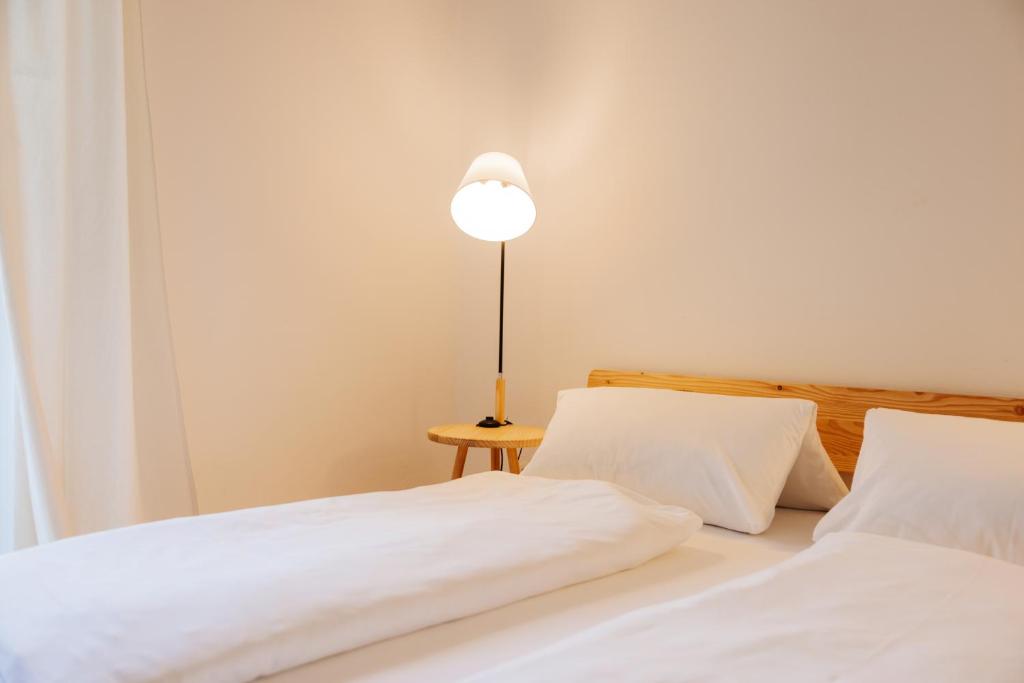 duas camas com lençóis brancos e um candeeiro sobre uma mesa em Boutiquehotel Lindenhof em Oberdrauburg