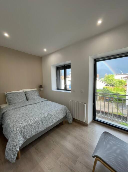 une chambre avec un lit et une grande fenêtre dans l'établissement Appartement cosy Champagnole, à Champagnole