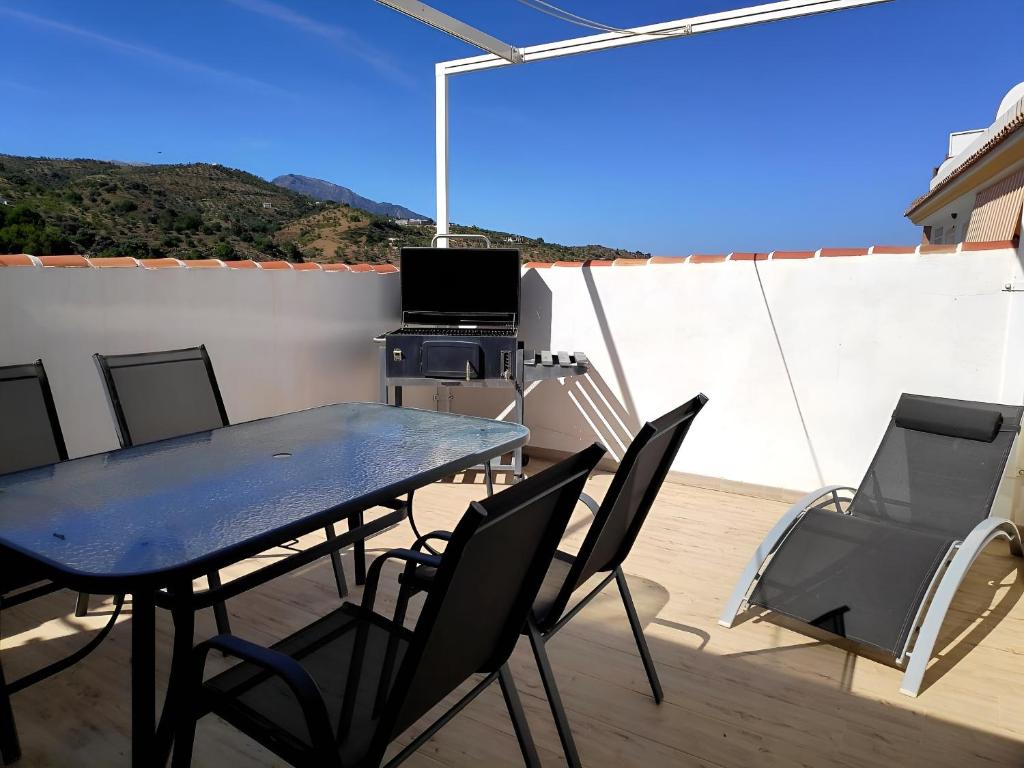 una mesa y sillas en un patio con TV en Apartamento El Almencino, en Tolox