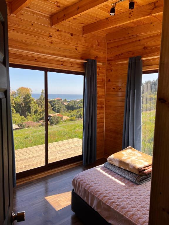 ein Schlafzimmer mit einem Bett und einem großen Fenster in der Unterkunft Cabañas Luz de Luna, Playa Curanipe in Curanipe