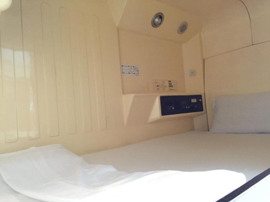 Pokój z łóżkiem i zegarem na ścianie w obiekcie Capsule Inn Hamamatsucho - Vacation STAY 68799v w Tokio