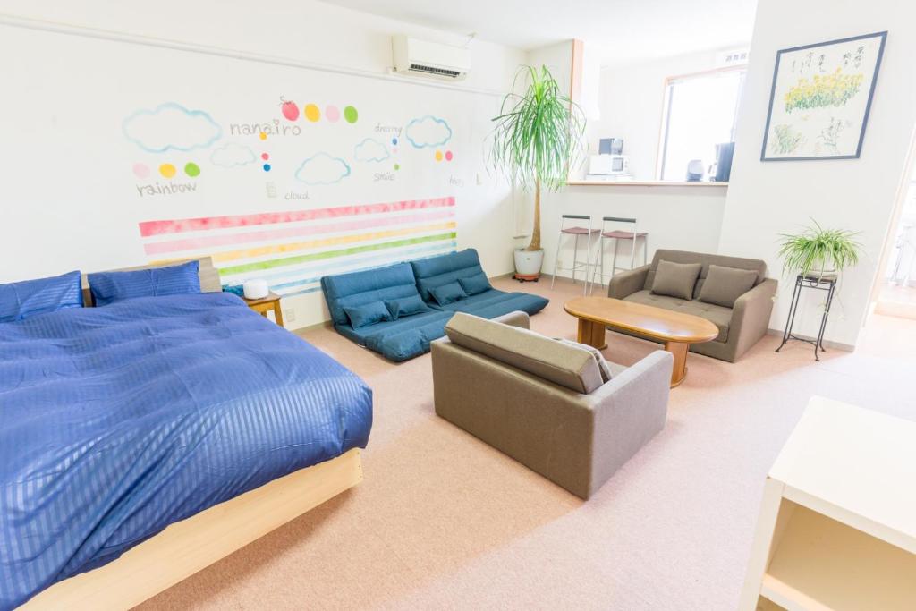 1 dormitorio con cama, sofá y sillas en GUEST HOUSE BLUE DOORS - Vacation STAY 73130v, en Yamagata
