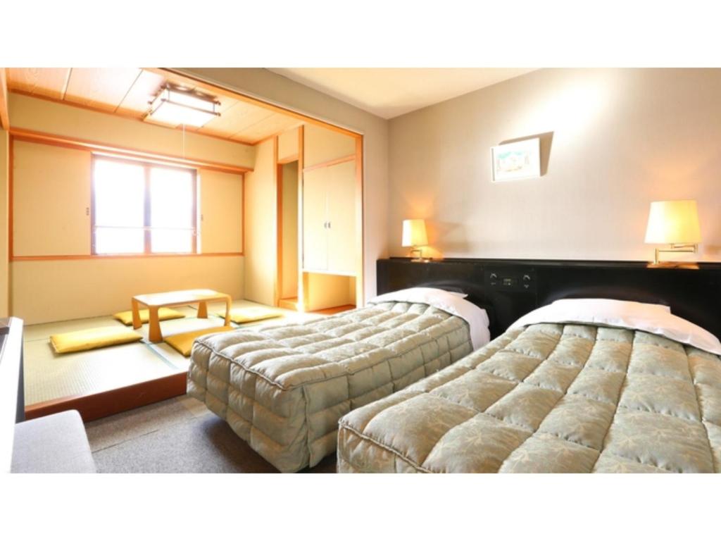 飯山市にあるHotel Silk in Madarao - Vacation STAY 79648vのベッド2台とテーブルが備わるホテルルームです。