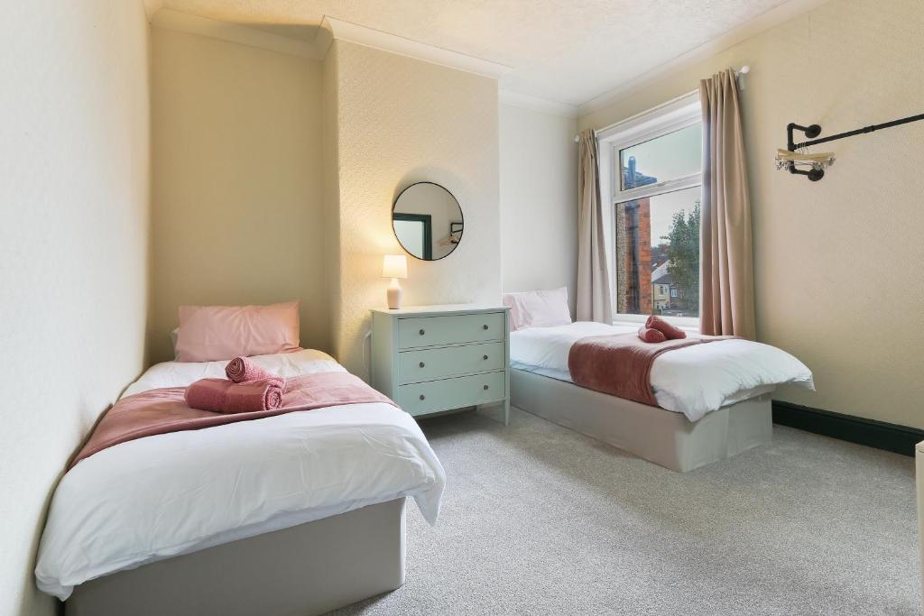a bedroom with two beds and a window at Home from Home 4 Bed - Ideal for Workers & Great for Groups, FREE Parking, Spacious, Pet Friendly Netflix in Kimberworth