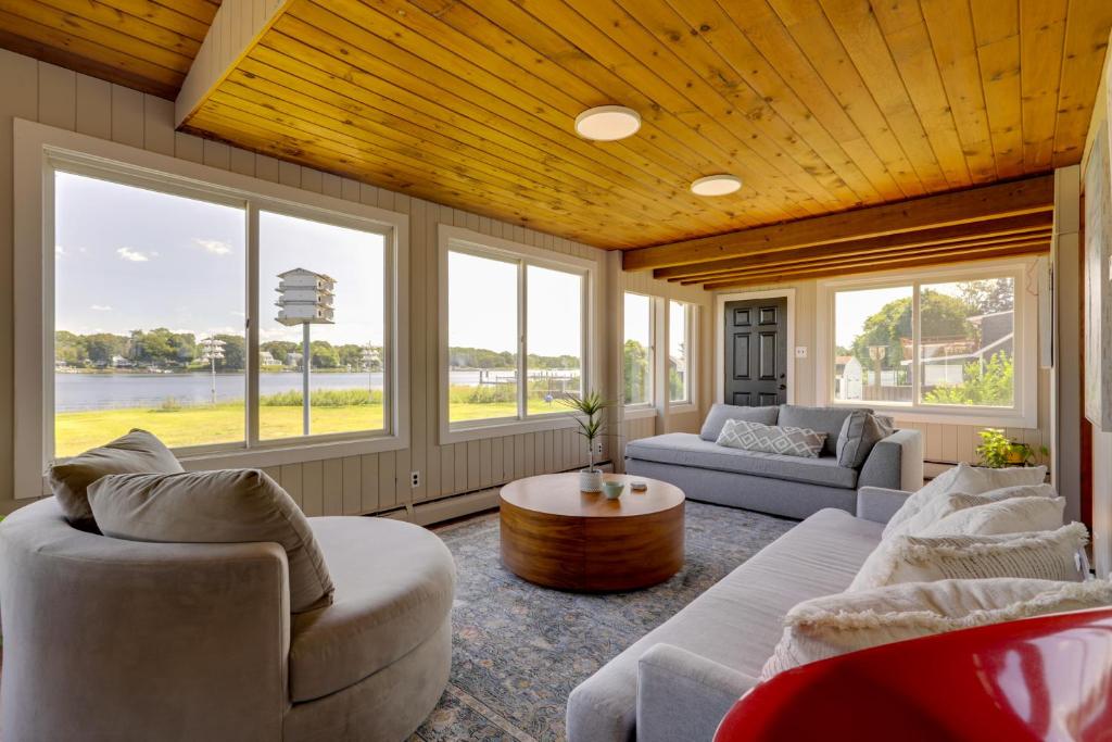 uma sala de estar com sofás, uma mesa e janelas em Waterfront Barrington Estate with Hot Tub! em Barrington