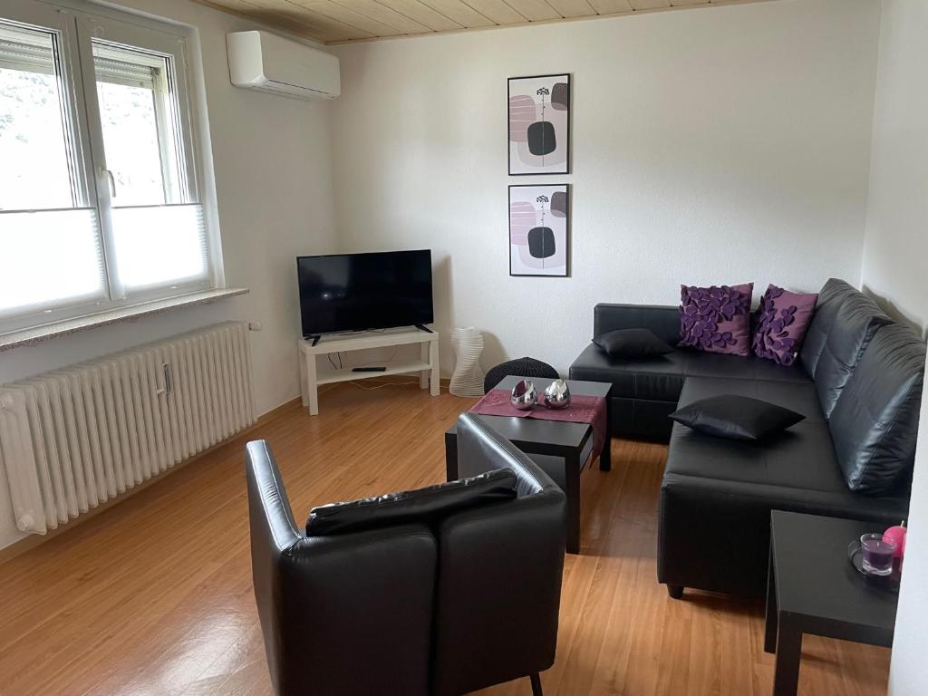 a living room with a black couch and a tv at Ferienwohnung Dieblich an der Mosel in Dieblich