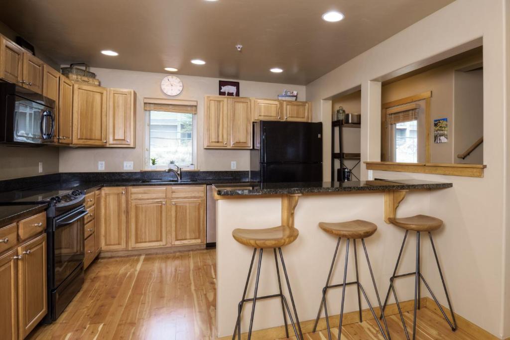 a kitchen with wooden cabinets and a counter with stools at Deer Run Condo - 12 Blacktail Buck in Big Sky
