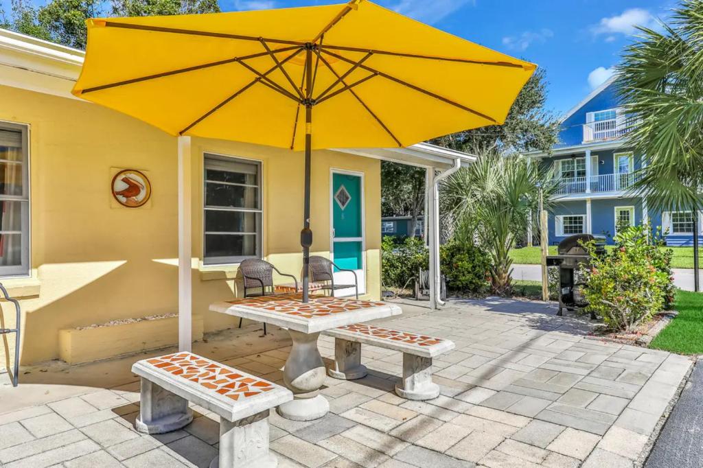 a yellow house with a picnic table and an umbrella at Pelican Beach Studio #6 in Clearwater Beach