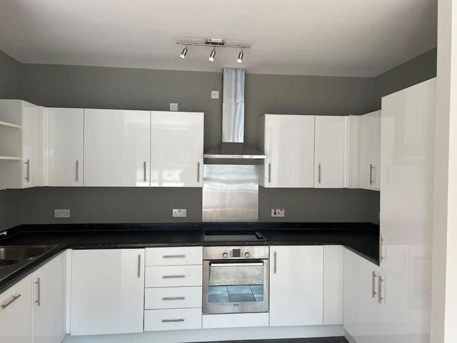 a kitchen with white cabinets and a stove top oven at Modern 2 Bed Apartment Next To Station + Parking in Beckenham