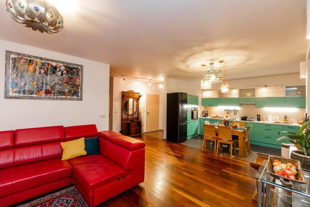 a living room with a red couch and a kitchen at Stunning apartment. Garage. Security. Mokotów area in Warsaw