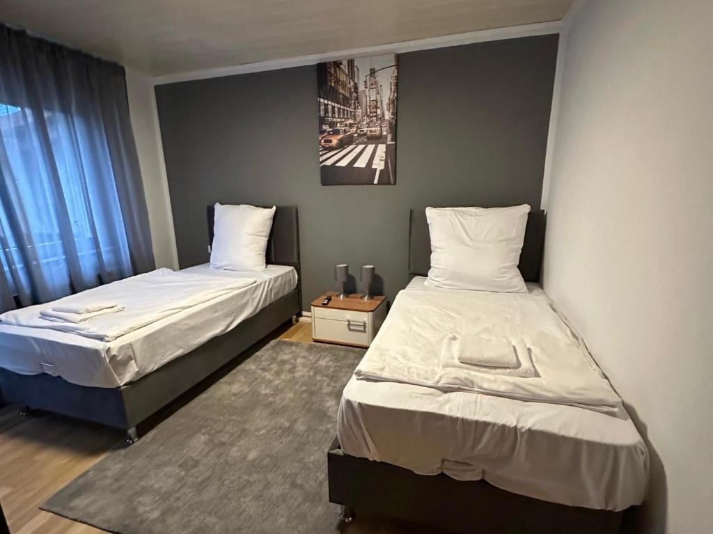 a bedroom with two beds and a picture on the wall at bee Apartment: Ideal für Gruppen & Monteure in Lahnau