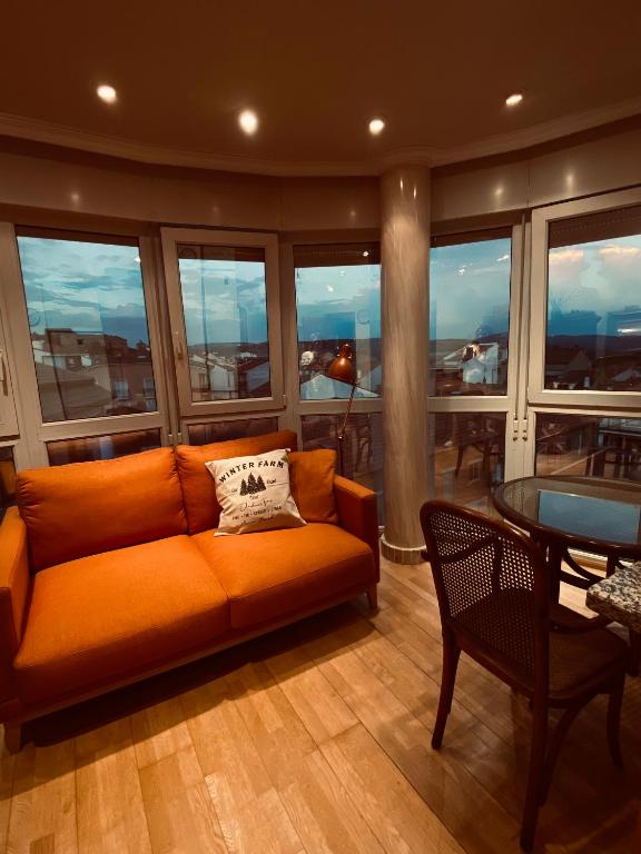 a living room with an orange couch and a table at El Rincón del Marqués in Las Navas del Marqués