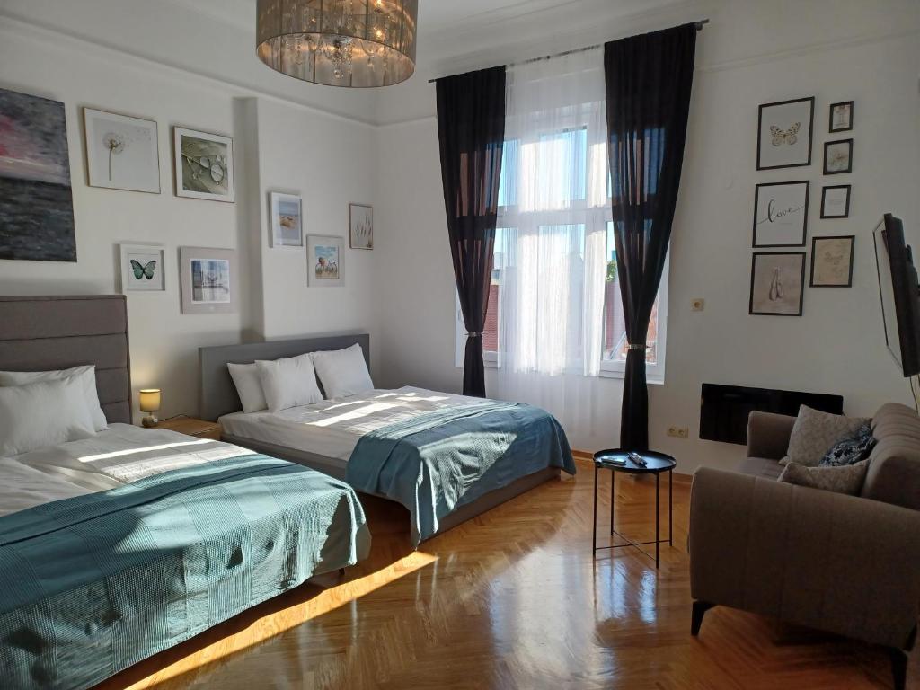 a bedroom with two beds and a couch and a window at Apartment Hesperia in Zagreb