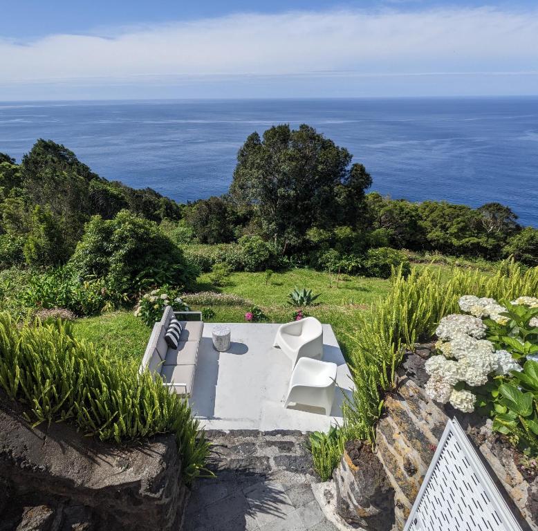 un banco blanco sentado en la cima de una colina con el océano en Casas do Horizonte, en Ribeiras