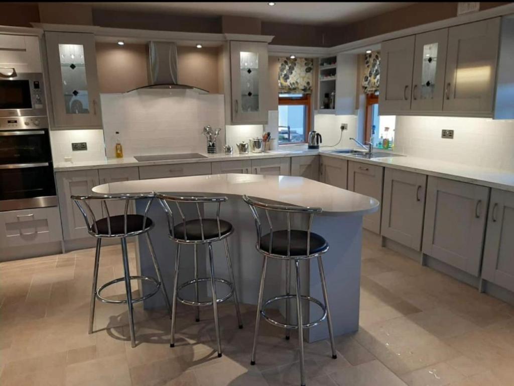 a kitchen with a large island with bar stools at The Lake House in Drumshanbo