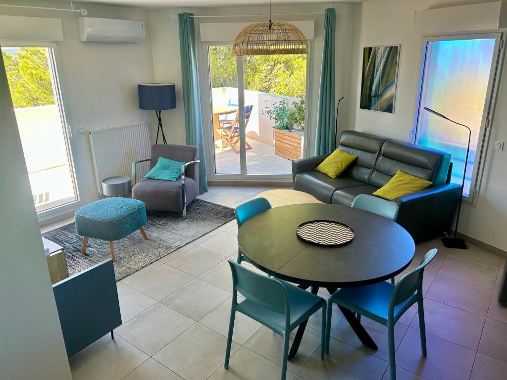 una sala de estar con un sofá, una mesa y sillas en BLUE NOTE -4 étoiles-Terrasse Vue-2 Parking, en Balaruc-les-Bains