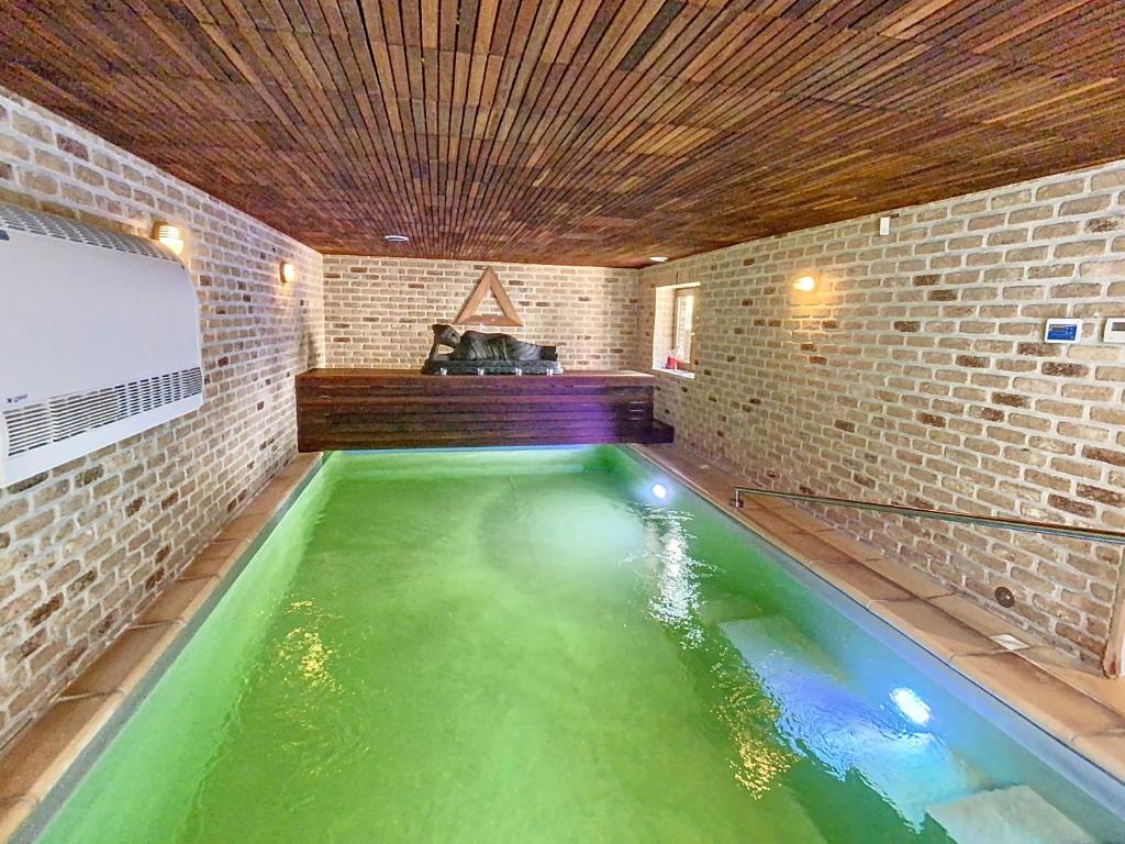 an indoor koi pond in a room with a brick wall at Appartement - Duplex 3 CH - 5 pers avec piscine intérieure privative Namur en pleine nature in Floreffe