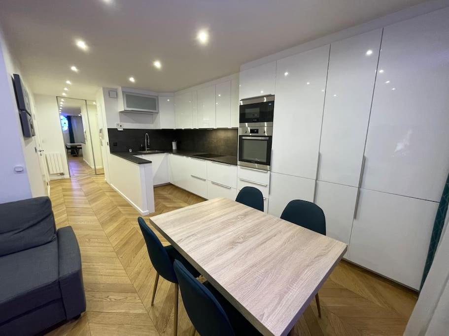 uma cozinha com uma mesa de madeira e cadeiras azuis em Appartement moderne de 2 pièces em Suresnes