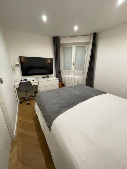 a bedroom with a bed and a desk and a television at Appartement moderne de 2 pièces in Suresnes