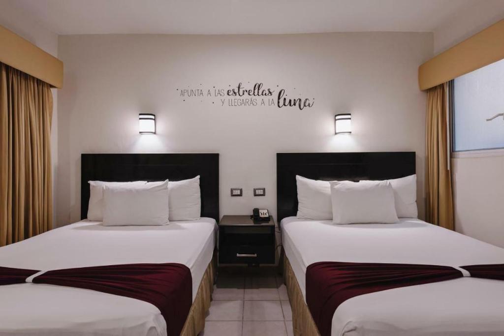 una habitación de hotel con 2 camas y un cartel en la pared en los rafeles 5 en Guaymas