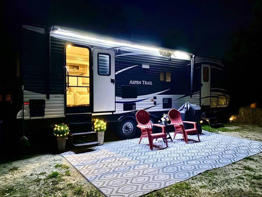 dos sillas y una mesa frente a una caravana en 63 Acre Farmstay - A luxury farm experience en San Mateo