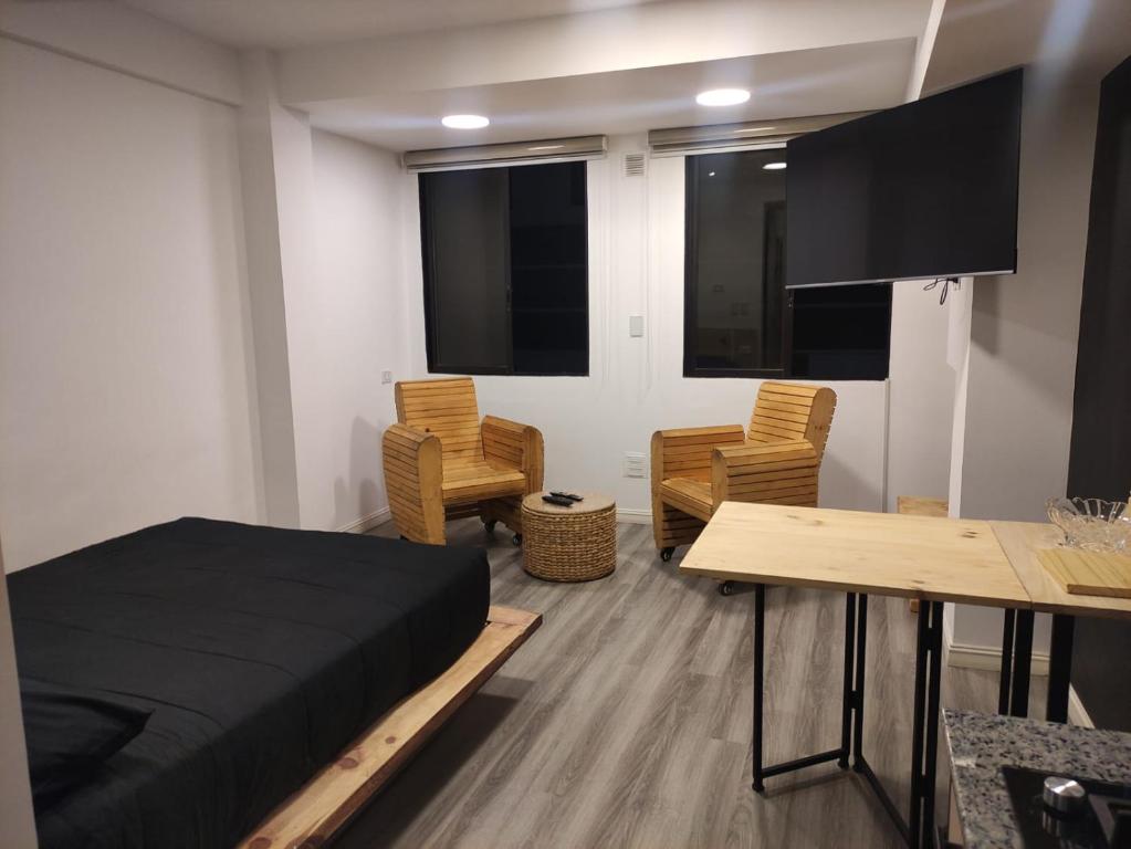 1 dormitorio con 1 cama, mesa y sillas en Bello Monoambiente en El Prado en Cochabamba