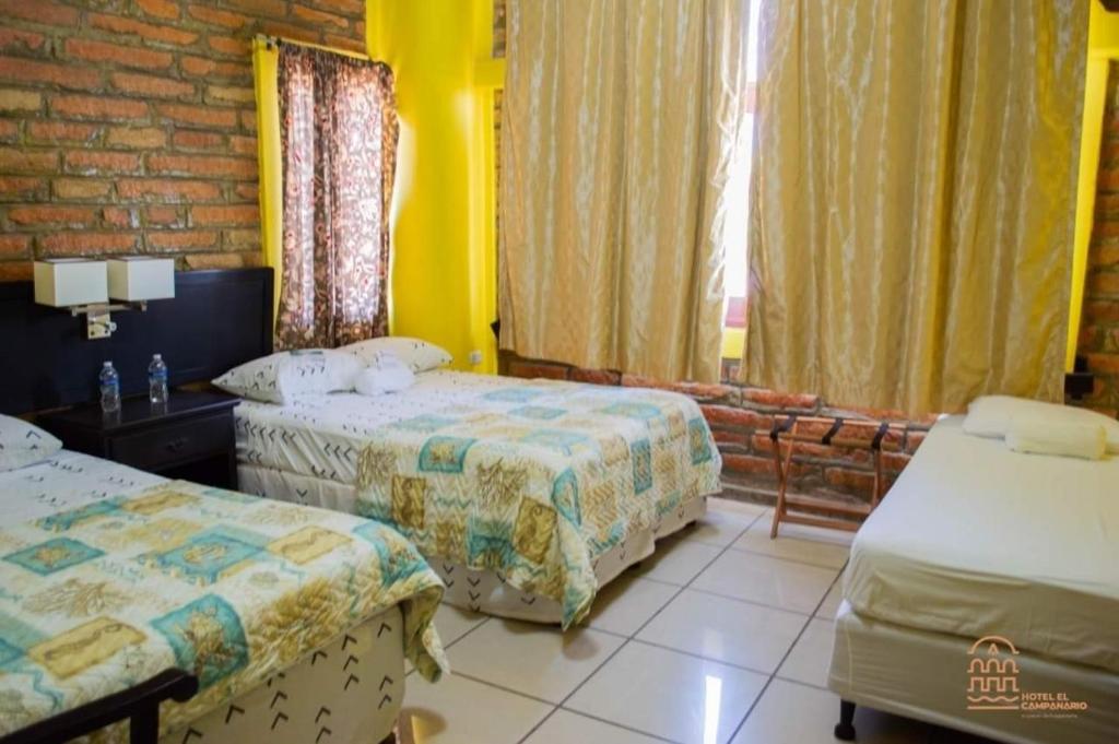 a hotel room with two beds and a window at Campanario in Comayagua