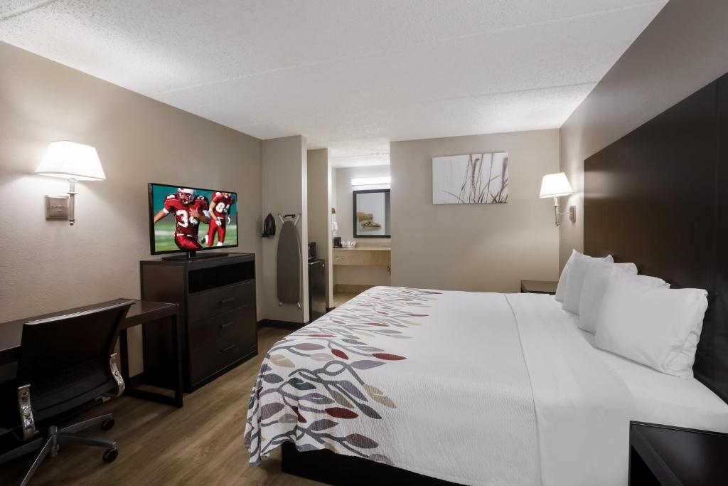 a hotel room with a bed and a desk and a television at Red Roof Inn Atlanta Airport NE Conley in Conley