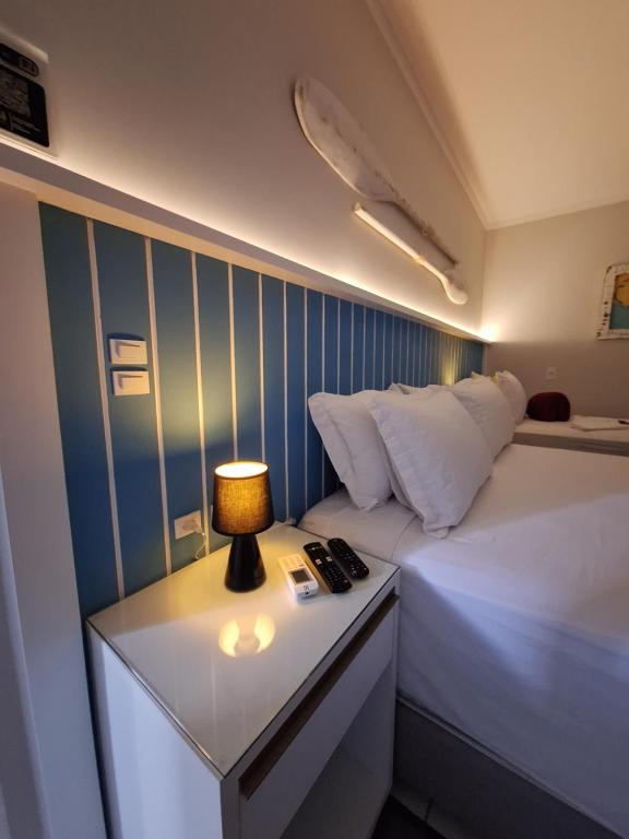 um quarto com uma cama e um candeeiro sobre uma mesa em NAVEGA PRAIA HOTEL em Navegantes