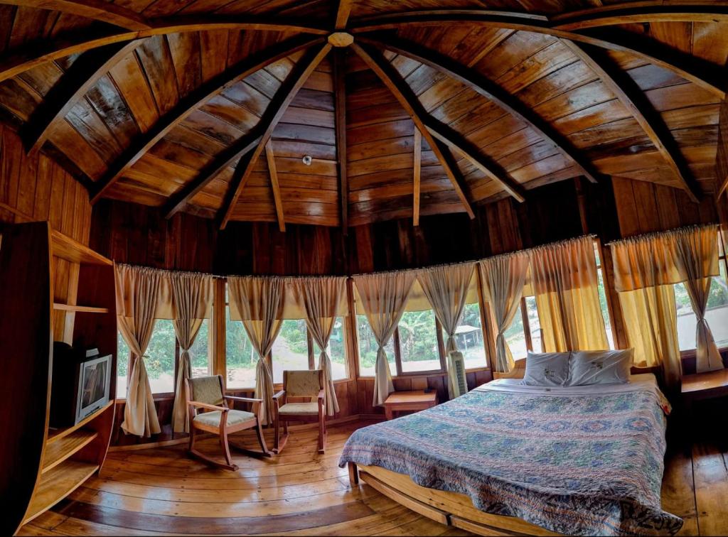 een slaapkamer met een bed in een kamer met een houten plafond bij HOTEL LAS TANGARAS DE MINDO in Mindo
