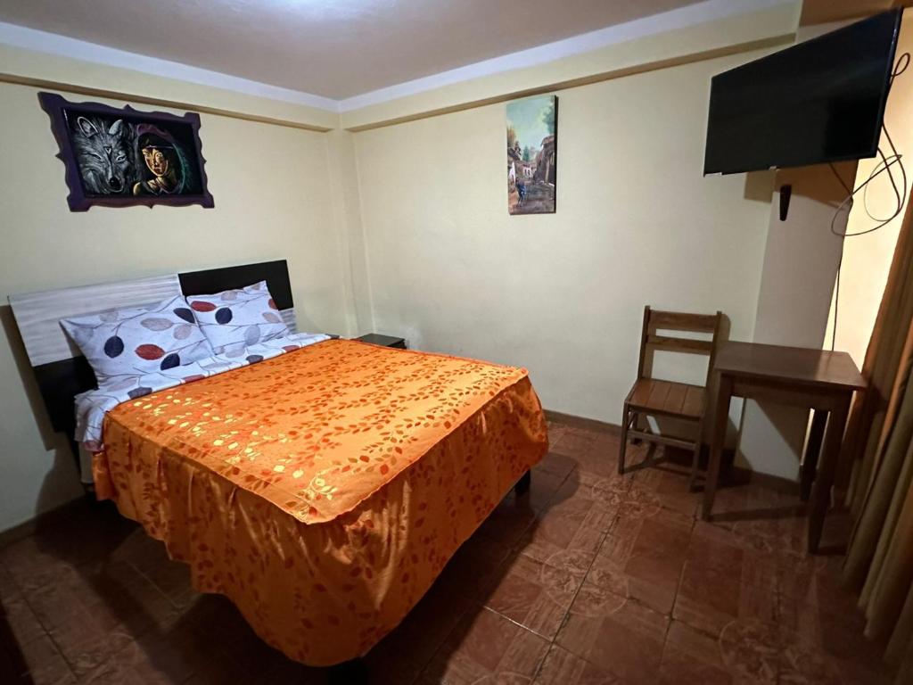 1 dormitorio con cama, mesa y TV en Hospedaje Qorichaska's en Cusco