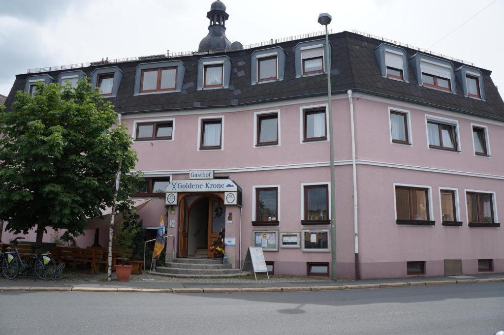 ein rosafarbenes Gebäude an der Ecke einer Straße in der Unterkunft Gasthof Goldene Krone in Selbitz