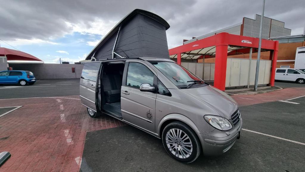 a small van parked in a parking lot with its door open at Camper in Los Cristianos