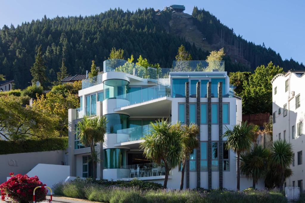 a building with palm trees in front of a mountain at Q1 Luxury Central Apartment in Queenstown